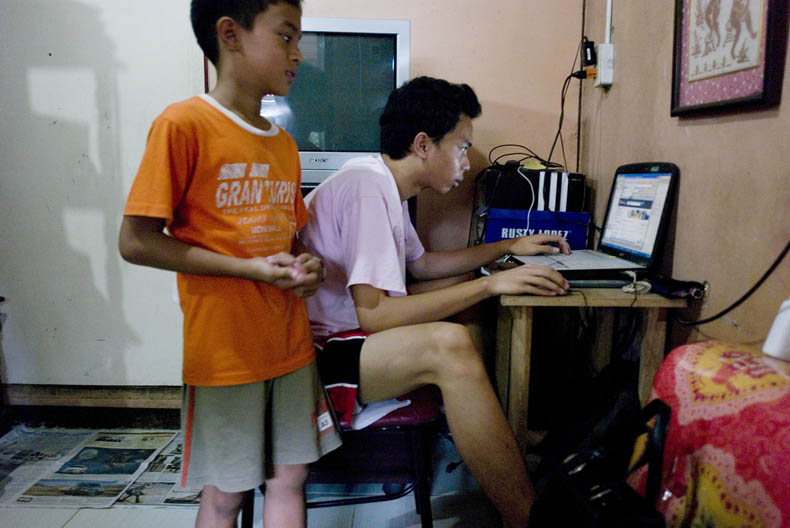 Twee jongens hebben via skype contact met hun vader die als vliegtuigmonteur in Bahrein werkt, Manila, Filippijnen